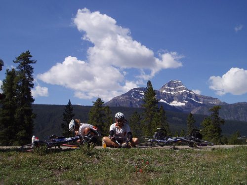 Libby Peterek fixing a flat and Tess sitting cross legged on a descent in Canada