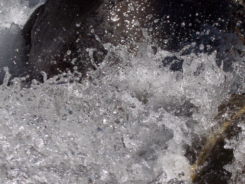 Close up of water rushing in a river against rocks